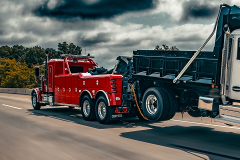 Century 5230 on a red peterbilt 589 chassis towing dumptruck on highway